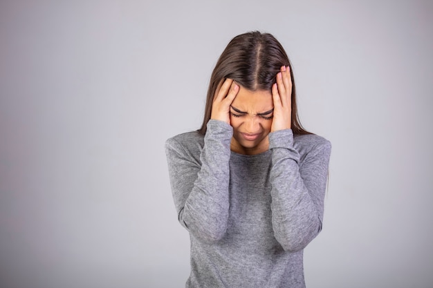 Photo woman holding hands to her temples having terrible headache.