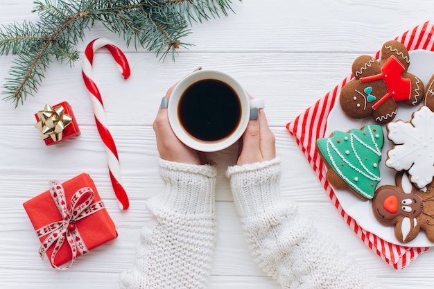 クリスマスの装飾で手のひらのコーヒー、キャンディー・キャンデーを手に持つ女性。