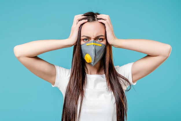 Woman holding head wearing respirator mask