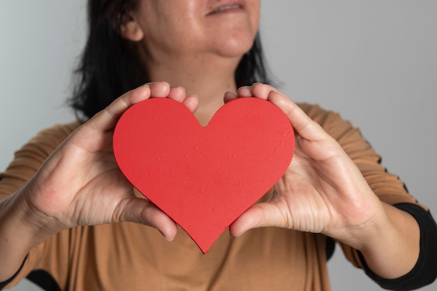 Woman holding a heart design in front of her neck