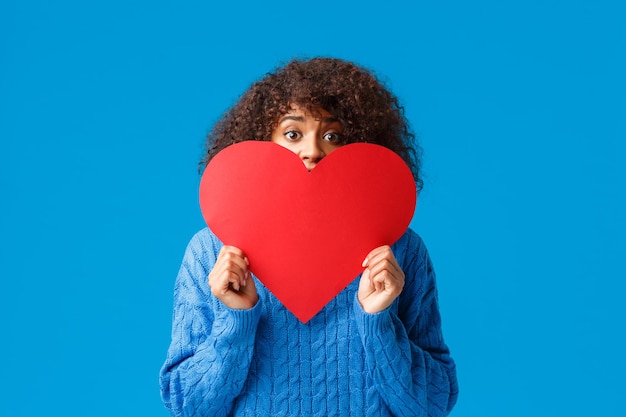 Woman holding heart shape against blue background