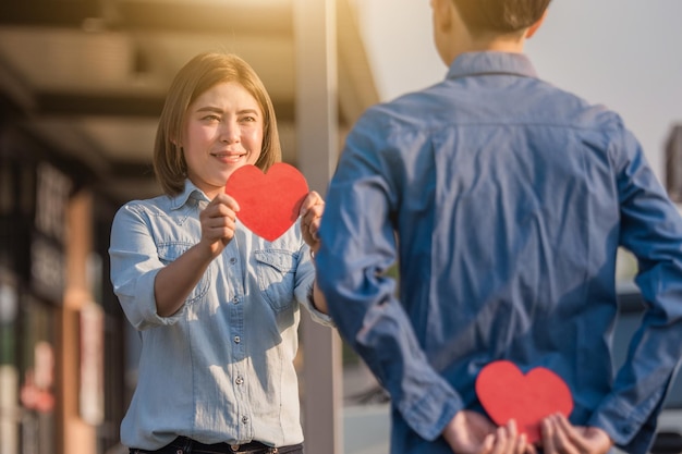 Photo woman holding heart shape while standing against people