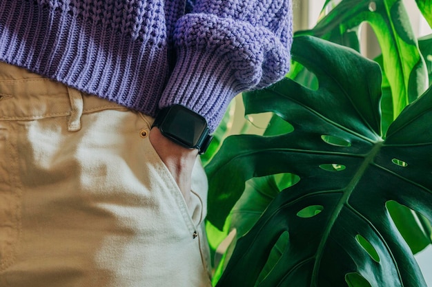 Foto donna che tiene la mano con un orologio in tasca su uno sfondo di palme