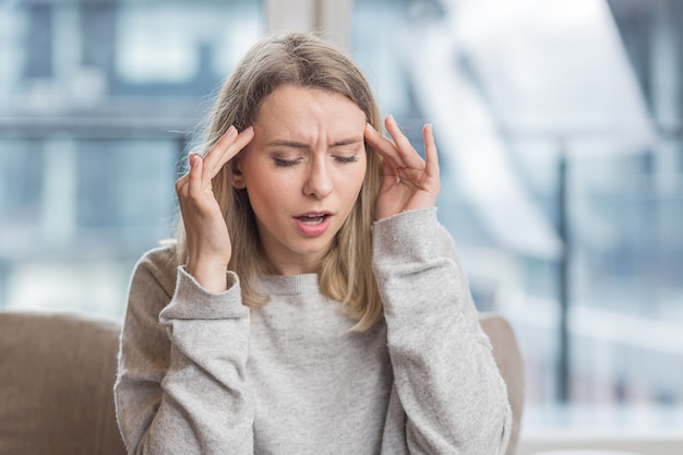  woman holding her head anxious about an unbearable headache