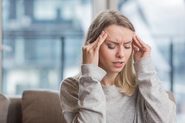Una donna che si tiene la testa in ansia per un mal di testa insopportabile