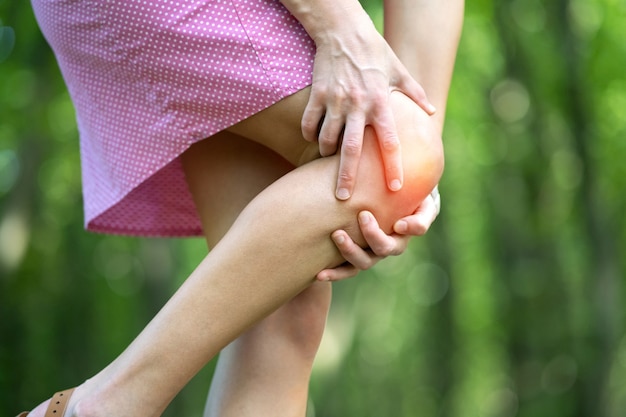 Woman holding her knee with hands having strong pain.