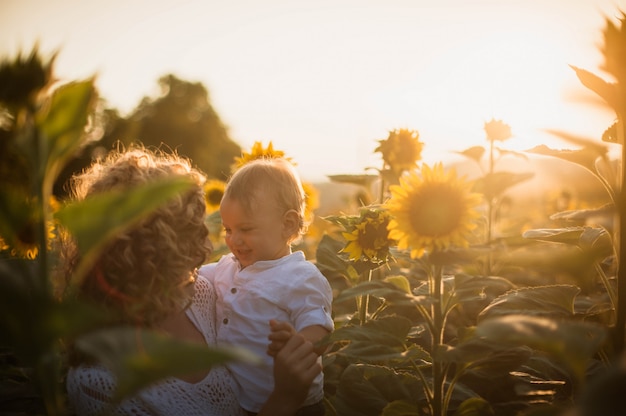 Woman holding her son amidst sunflower field