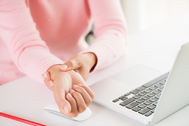 Woman holding her wrist pain from using computer. Office syndrome