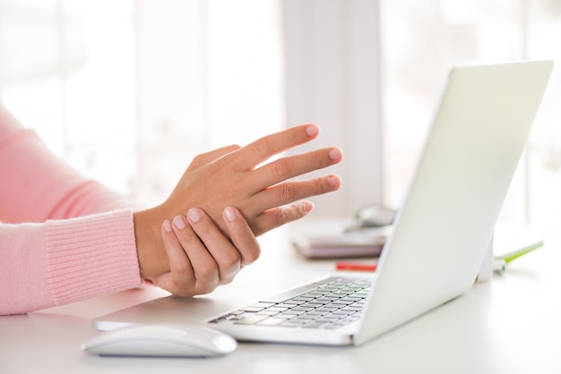 Woman holding her wrist pain from using computer. Office syndrome.