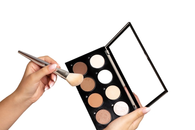Woman holding highlighting and contouring kit with a brush isolated on a white background