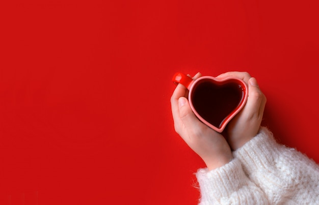 Woman holding hot cup of coffee, with heart