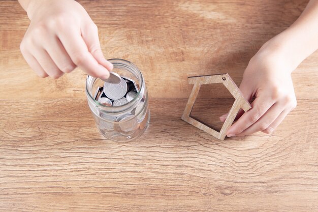 woman holding a house and a jar of coins