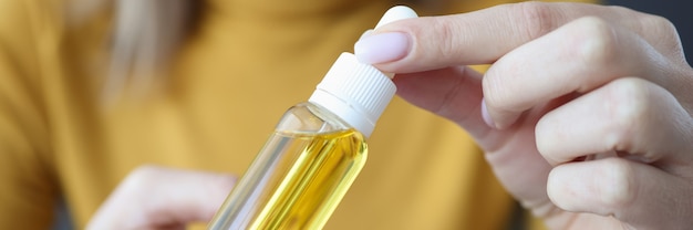 Woman holding jar of hair oil in her hands closeup