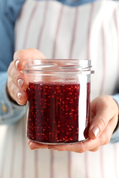 Woman holding jar of raspberry jam in hands, close up