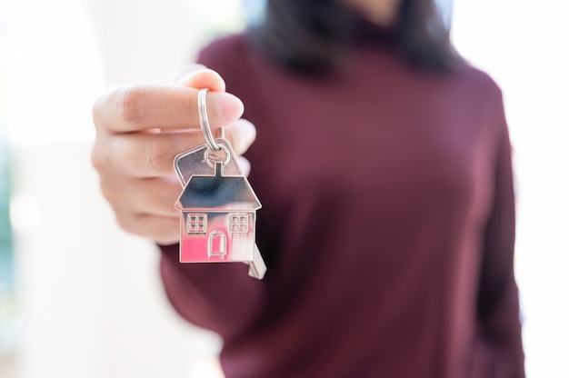 Woman holding keychains house key. Property investment and house mortgage financial real estate concept