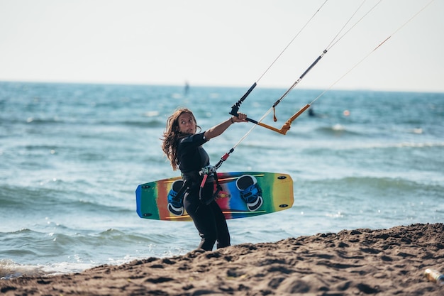 Woman holding kiteboard and going into the water