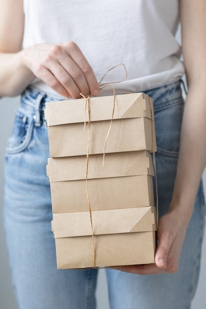 Woman holding kraft cardboard boxes food or clothing delivery\
modern ways to buy food with delivery