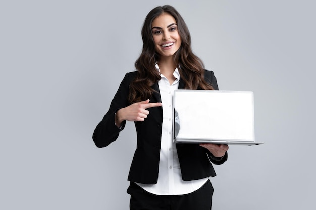 Woman holding laptop with empty mock up screen Portrait of a young happy business woman with a laptop over gray background