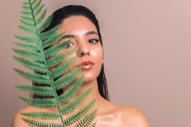 woman holding a leaf hiding behind it