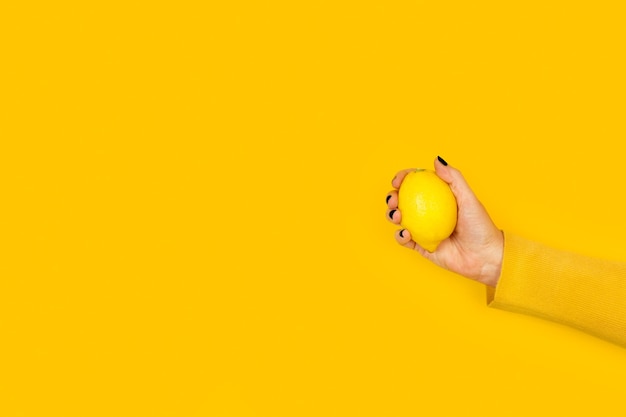 Photo woman holding a lemon on a yellow background