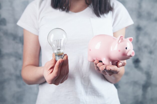 Photo woman holding a light bulb and a piggy bank