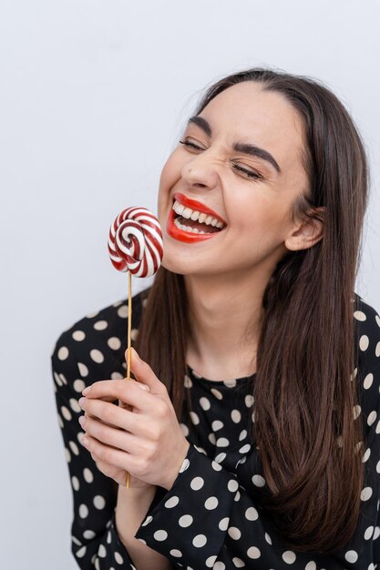 Photo a woman holding a lollipop with a smile on her face the joyful woman delighting in a colorful lollipop