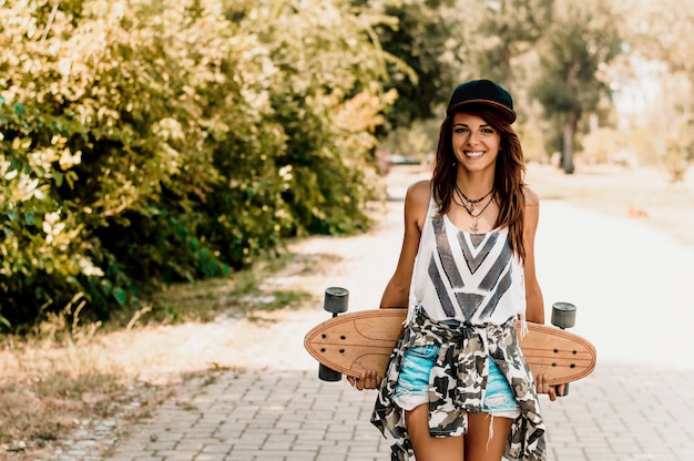 Woman holding longboard behind her back.