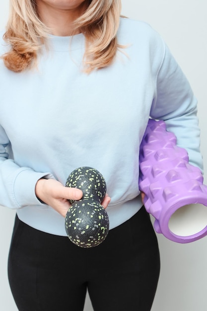 Foto donna con dei rulli di massaggio per il rilascio miofasciale nelle mani un allenatore di fitness con oggetti per il liberamento miofasciale