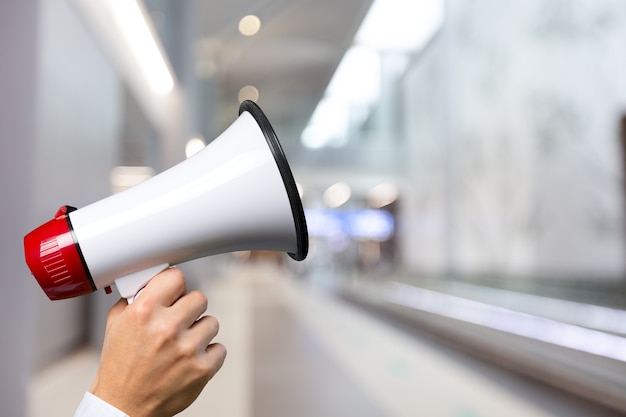 Woman holding megaphone on color background