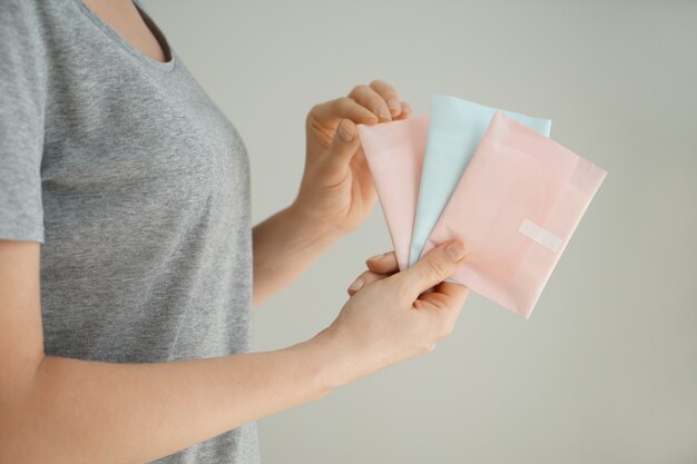 Woman holding menstrual pads on grey background