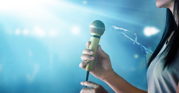 Woman holding microphone and singing on concert stage background