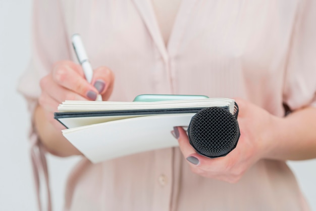 Photo woman holding microphone and writing notes