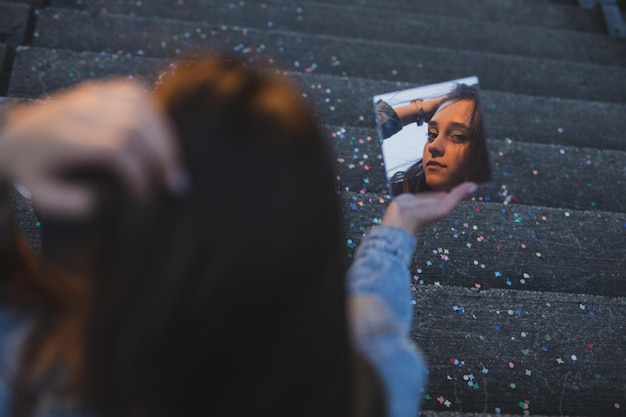 사진 다채로운 콘페티와 함께 계단에 거울을 들고 있는 여자