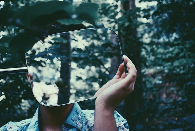 Photo woman holding mirror while standing in forest