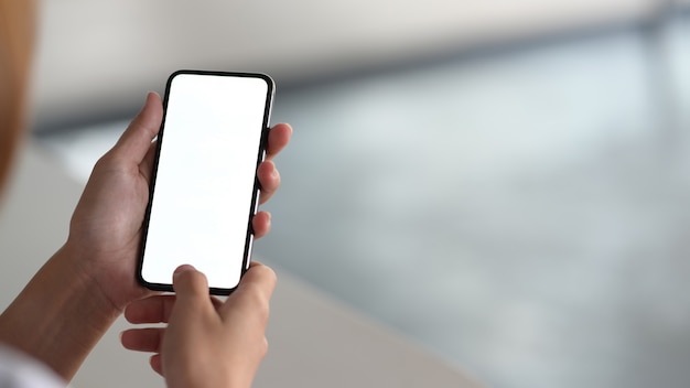 モバイルデバイスを保持していると空白の画面のスマートフォンに触れる女性
