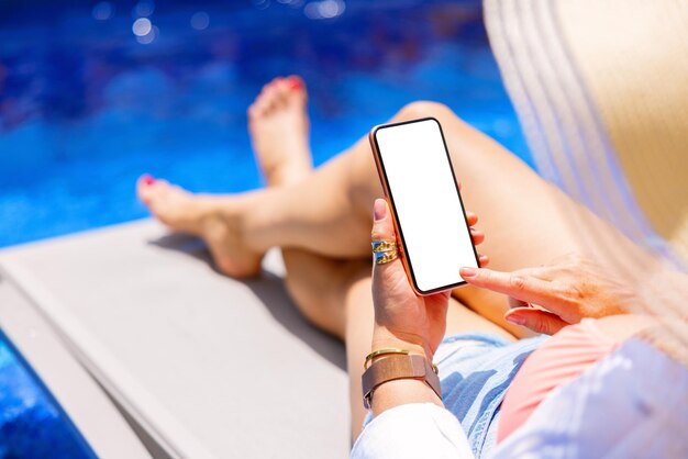 Woman holding mobile phone by the pool screen mockup