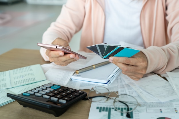 Telefono cellulare della tenuta della donna e carte di credito, conto e concetto di risparmio.