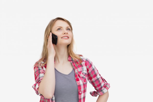 Woman holding a mobile phone while looking up