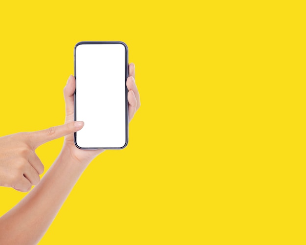 Woman holding mobile phone with blank screen on yellow wall, closeup