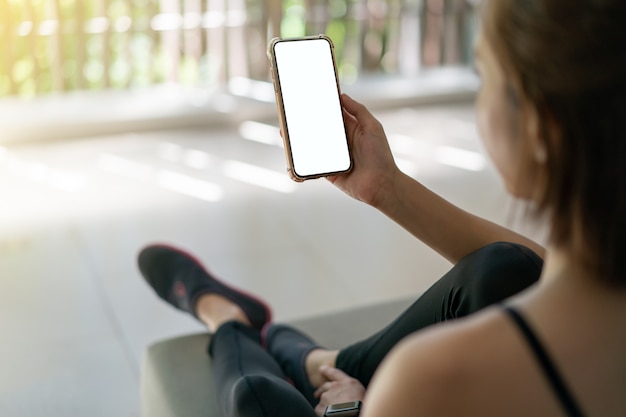 Woman holding mobile phone with blank white screen .