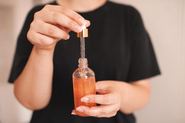 Woman holding moisturizing facial serum in glass bottle close up. Skin health care. Healthy lifestyle.