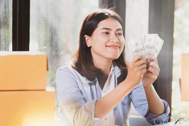 Le banconote dei soldi della tenuta della donna sorride con felice.