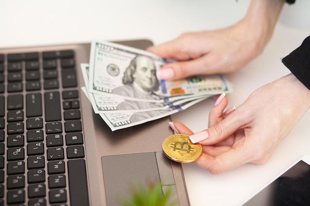 Woman holding money in hand near a laptop to buy btc