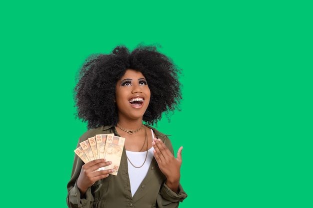 Woman holding money young smiling woman holding Brazilian money green background