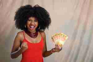 Photo woman holding money young woman holding brazilian money celebrating