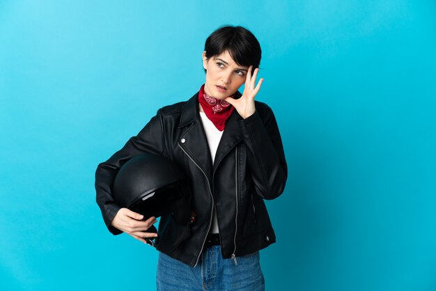 Woman holding a motorcycle helmet on blue with headache