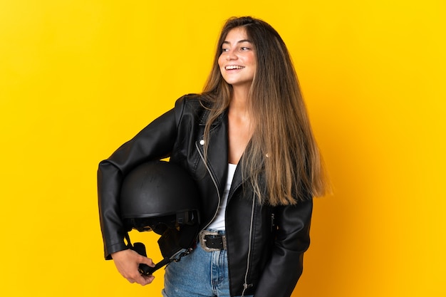 Женщина, держащая мотоциклетный шлем изолирована, глядя в сторону и улыбается