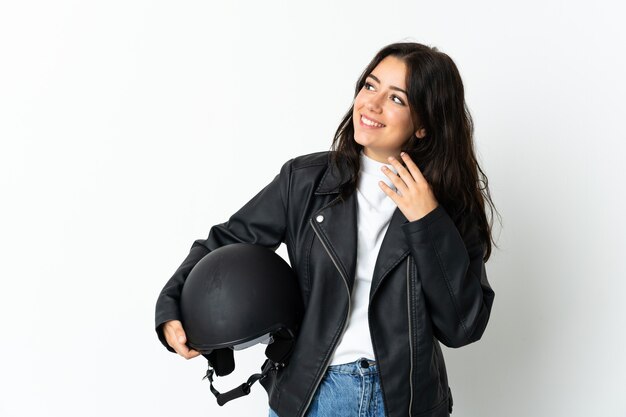 Woman holding a motorcycle helmet isolated on looking up while smiling