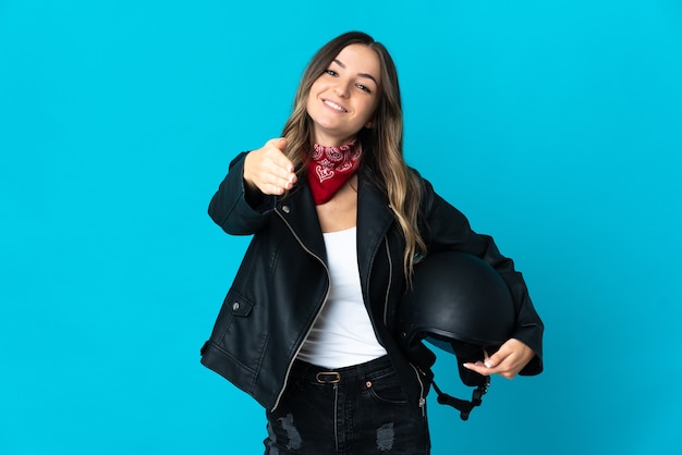 Woman holding a motorcycle helmet isolated shaking hands for closing a good deal