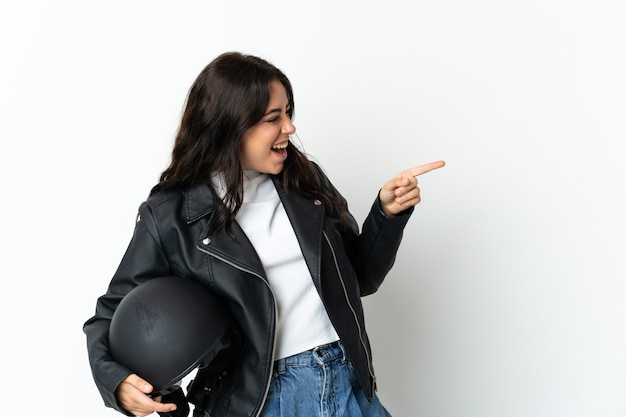 Donna che tiene un casco del motociclo isolato su priorità bassa bianca che indica il dito di lato e che presenta un prodotto